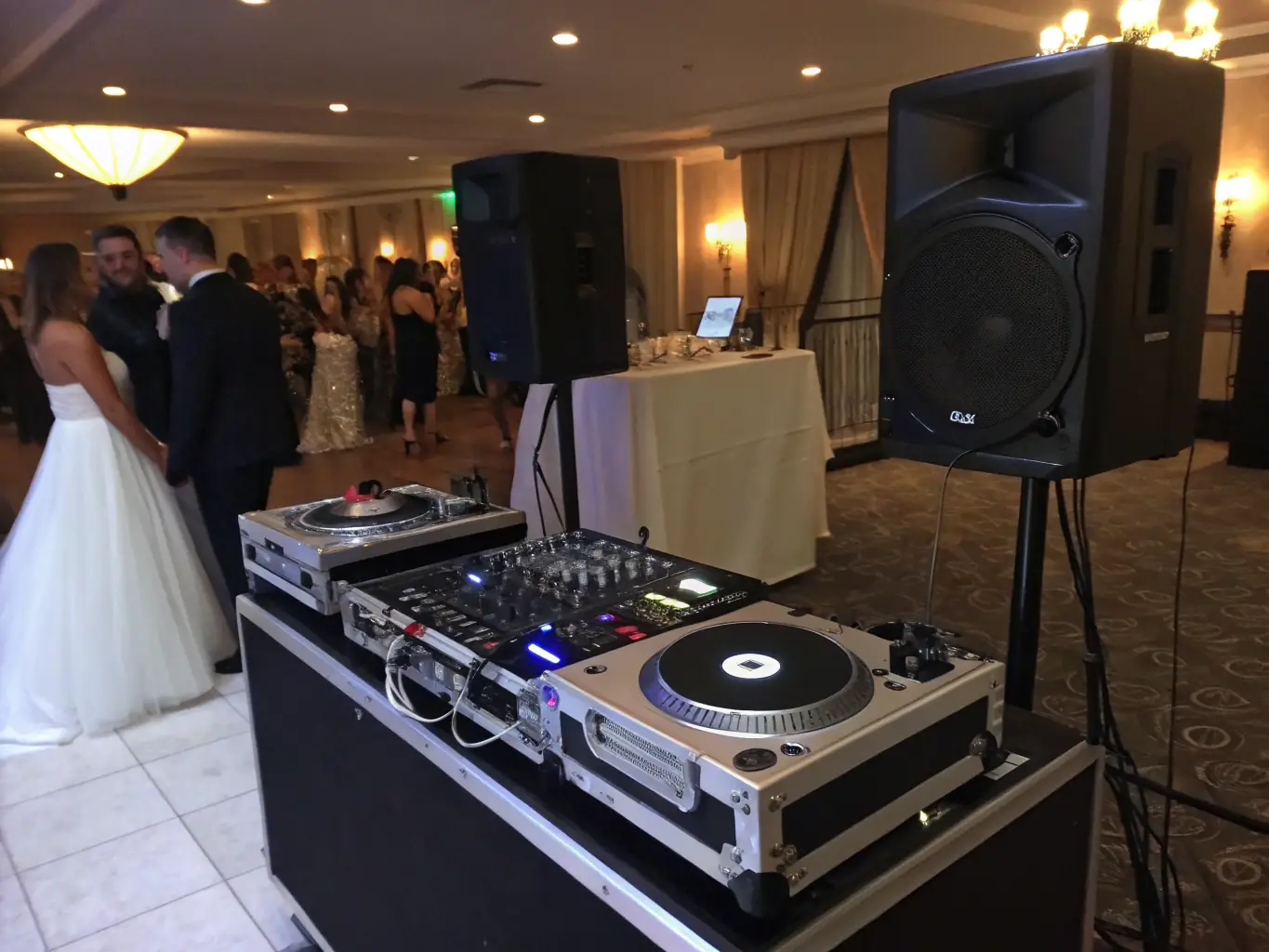 A professional shot of Annie Vegas's state-of-the-art DJ equipment setup at a wedding venue, featuring high-quality speakers, lighting, and mixing consoles, all meticulously arranged for optimal sound and visual impact.