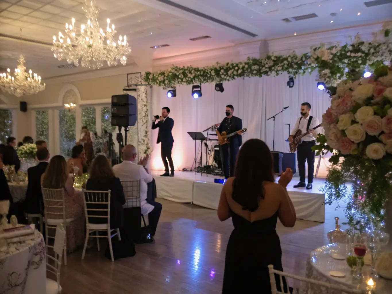 A jazz trio playing smooth tunes during a wedding cocktail hour, guests mingling and enjoying drinks in a stylish outdoor setting, soft lighting enhancing the relaxed atmosphere.